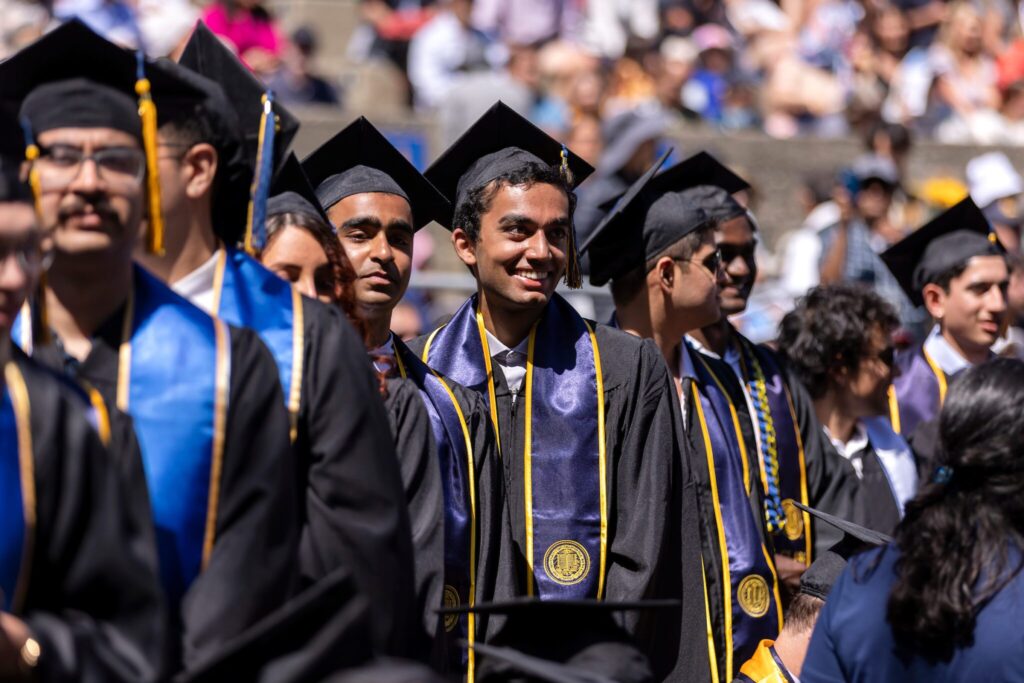Students standing together in caps and gowns at College of Engineering graduation